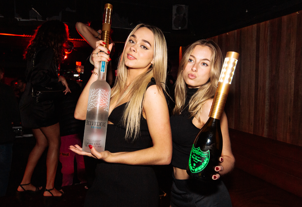 Gold LED bottle sparkler lights attached to Belvedere and Dom Pérignon bottles for premium nightclub bottle service