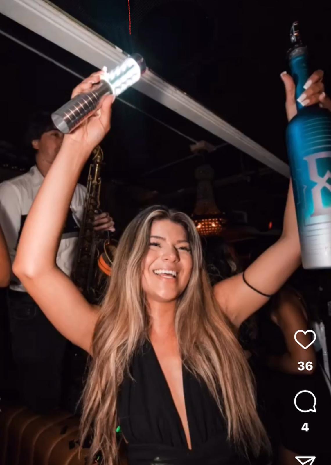 LED bottle service sparkler light baton held up beside a magnum of Vodka by a VIP host during a bottle service show in a lounge